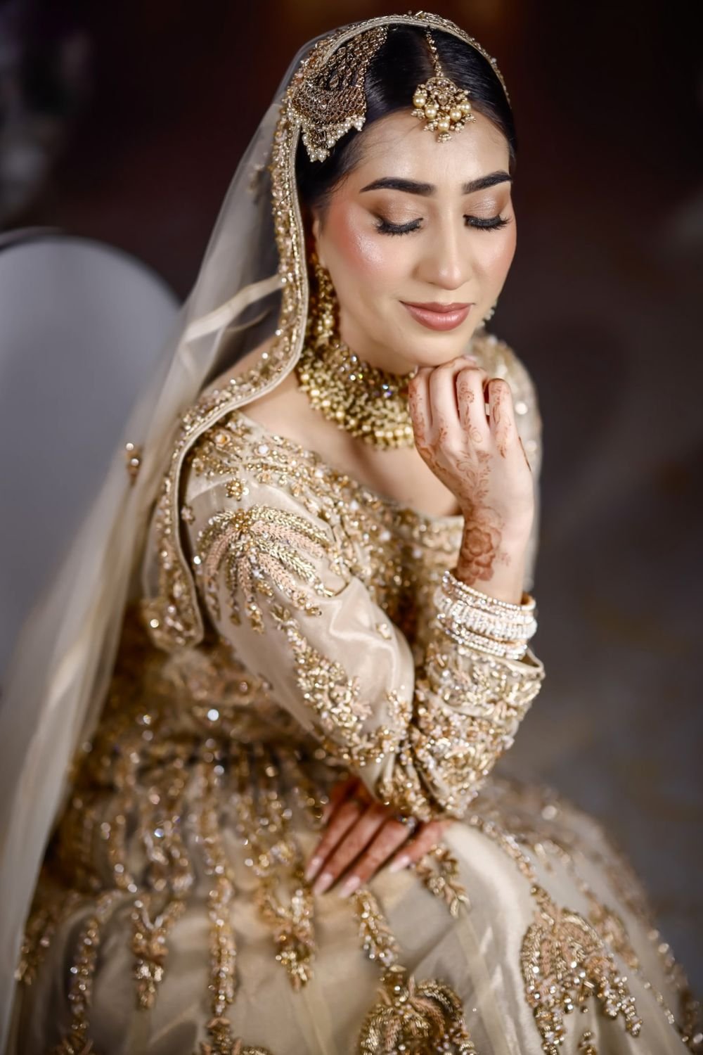 Bride in gold, framed by her dupatta