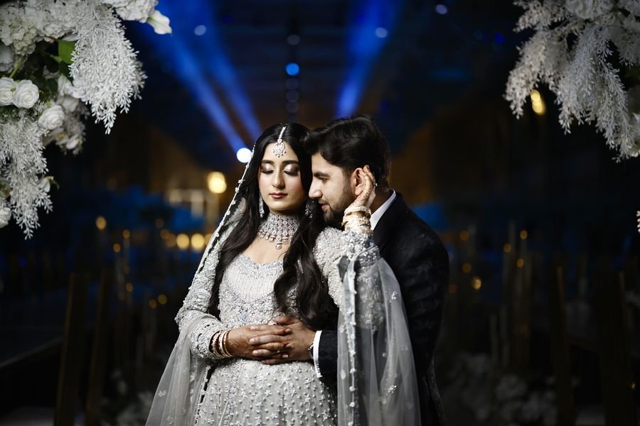 Bride and groom beneath blue lights at night