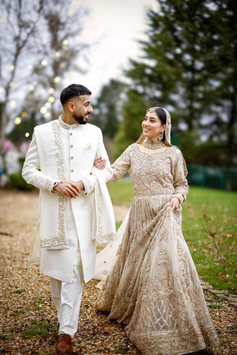 Bride and groom walking arm in arm through a garden
