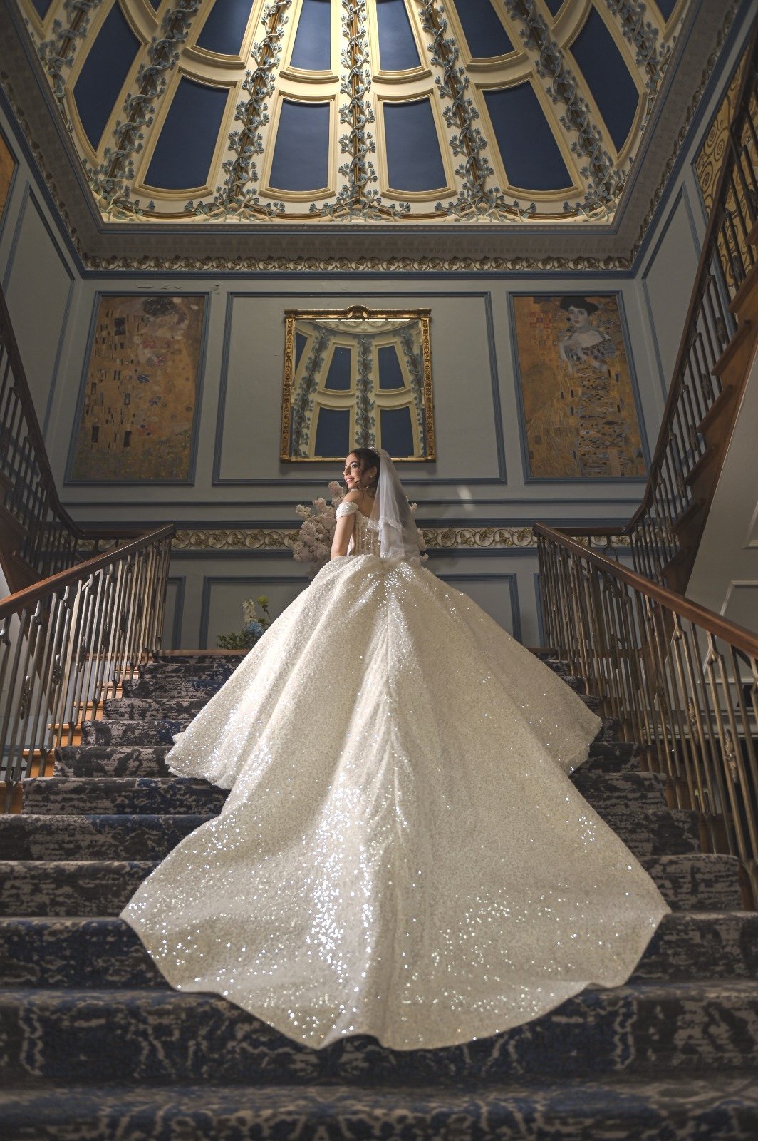 Bride in a flowing gown on a grand staircase